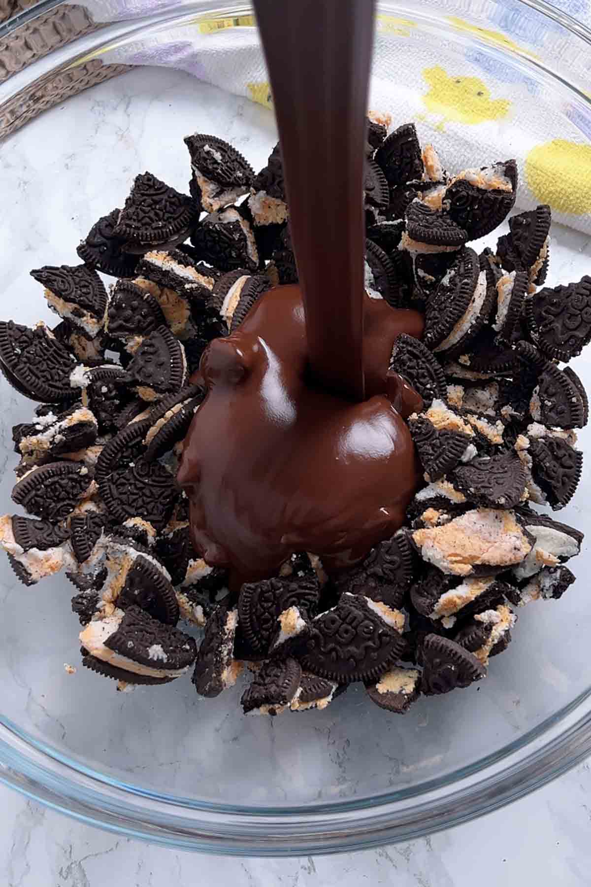 pouring melted chocolate mixture into bowl of biscuits