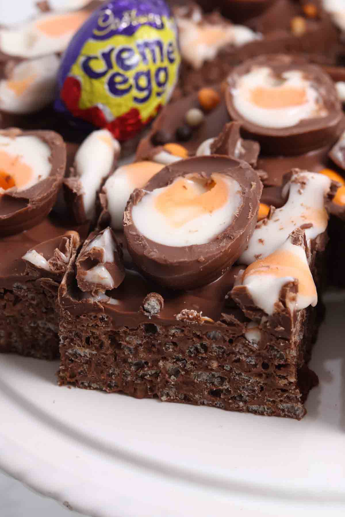 squares of creme egg rice krispie treats on a white cake stand