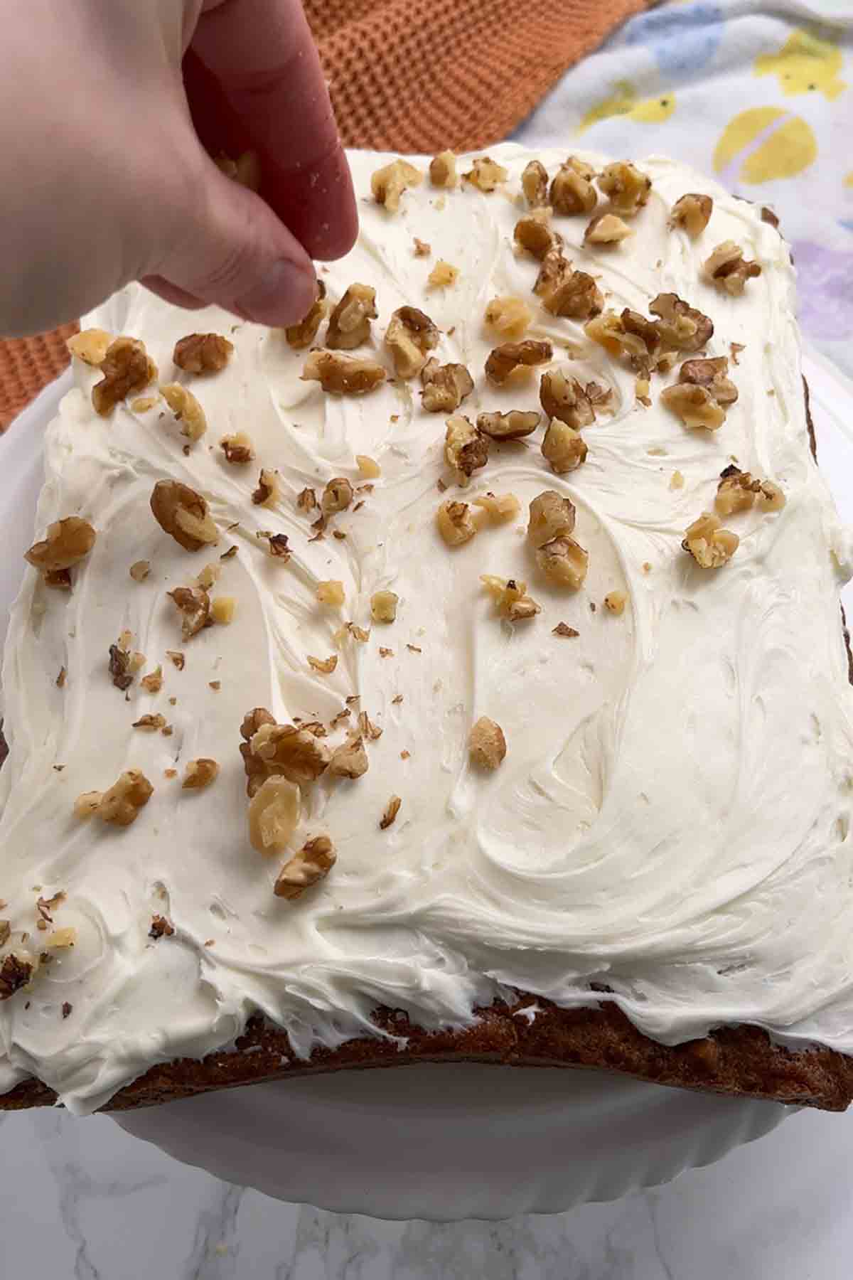 sprinkling walnuts over the cream cheese icing