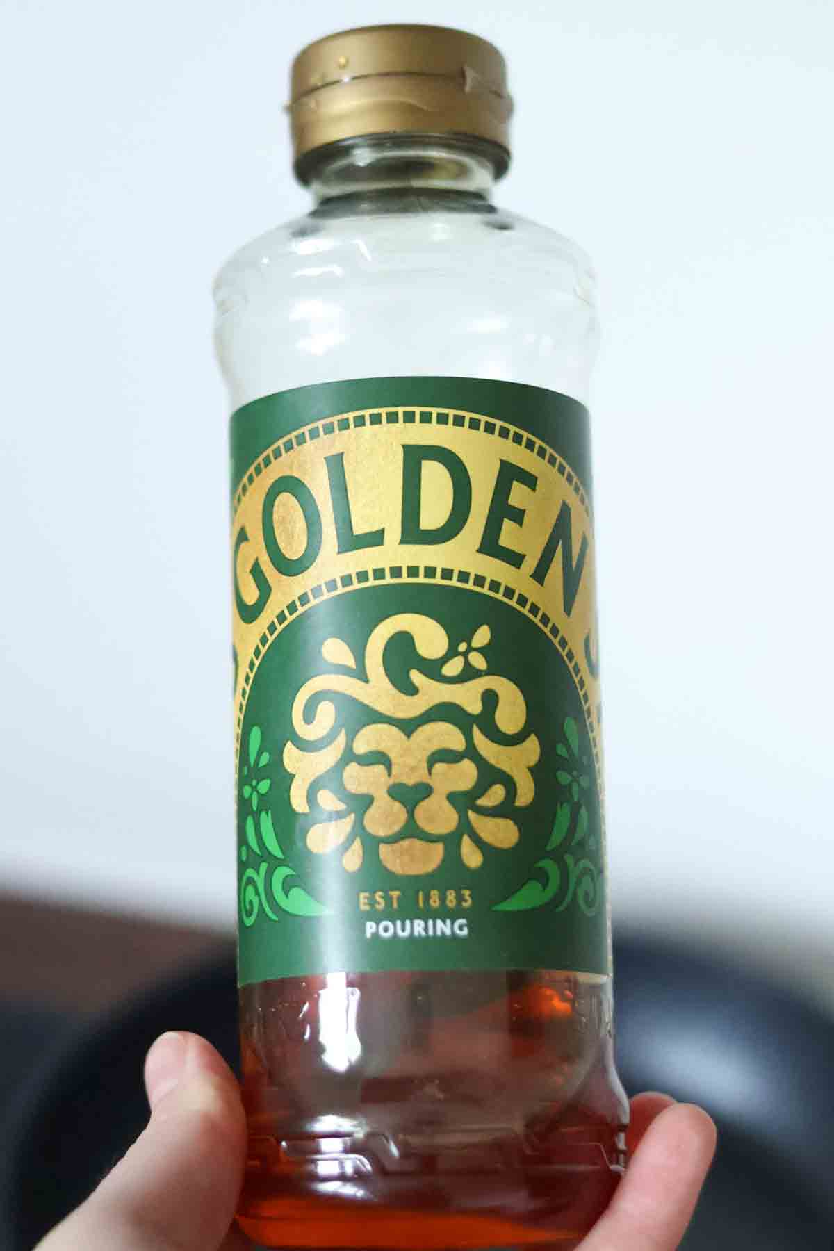 hand holding up a bottle of golden syrup