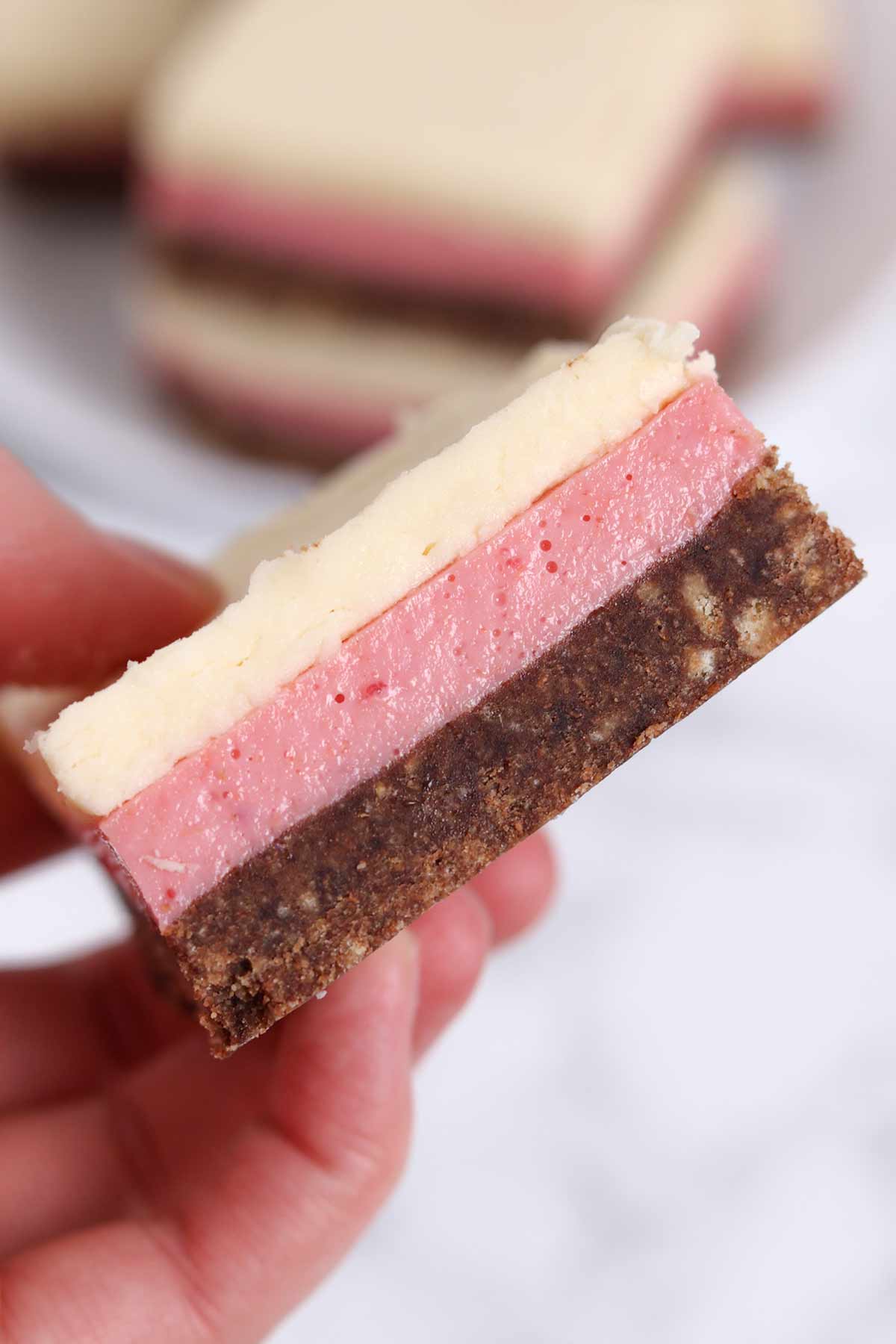 hand holding up a slice of neapolitan traybake