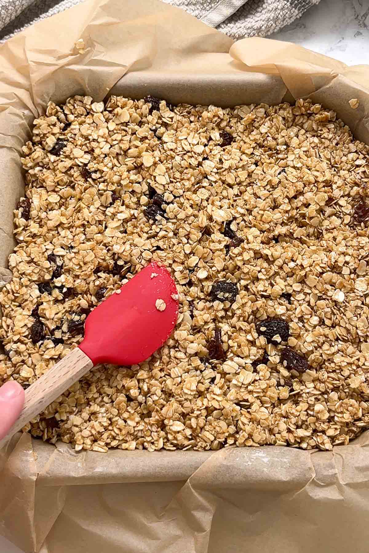 pressing the oaty mixture into lined tin