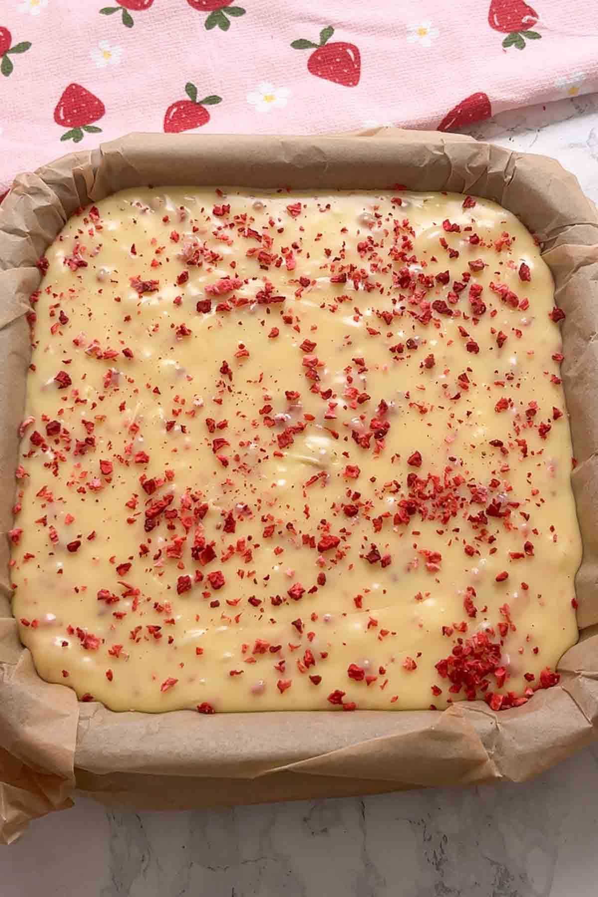 mixture in lined tin topped with freeze dried strawberry pieces