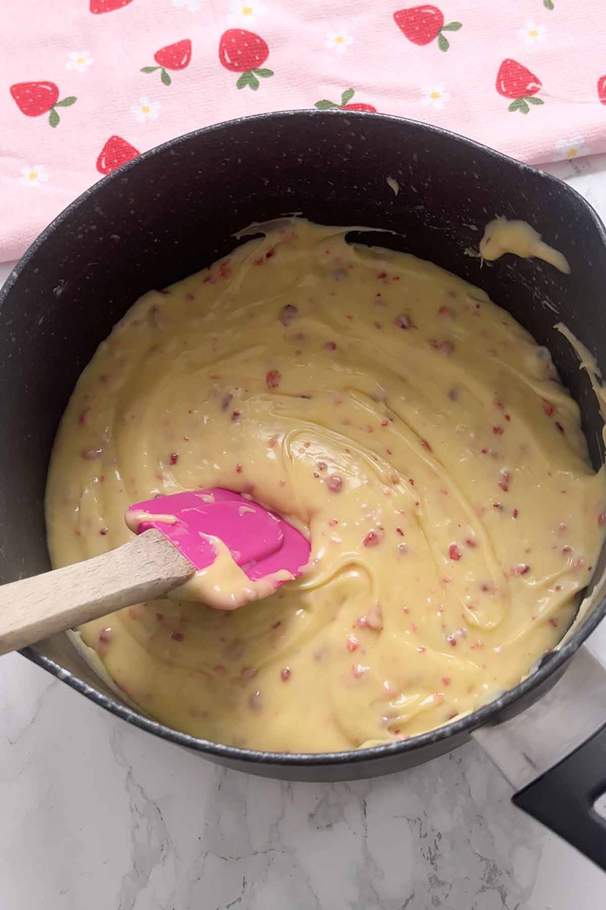 mixture in saucepan with strawberry pieces mixed in
