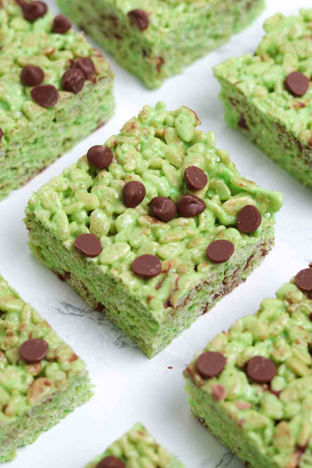 squares of mint chocolate chip rice krispie treats on a white surface